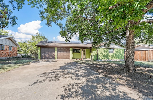 single story home featuring solar panels and a garage