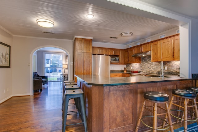 kitchen with crown molding, stainless steel appliances, dark hardwood / wood-style flooring, and kitchen peninsula