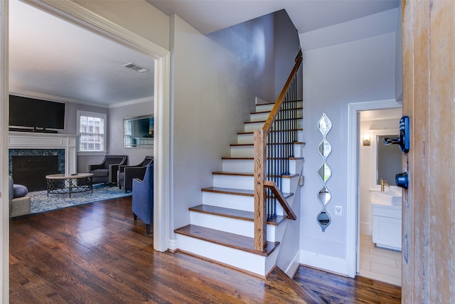 stairs with crown molding, hardwood / wood-style flooring, and a fireplace