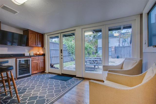 entryway with wood-type flooring, a wealth of natural light, and beverage cooler