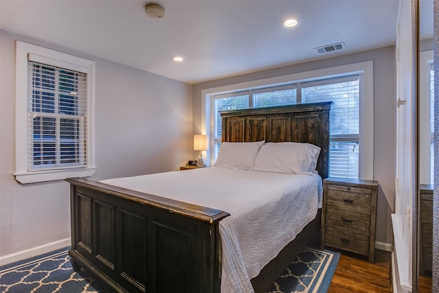 bedroom with multiple windows and dark hardwood / wood-style floors