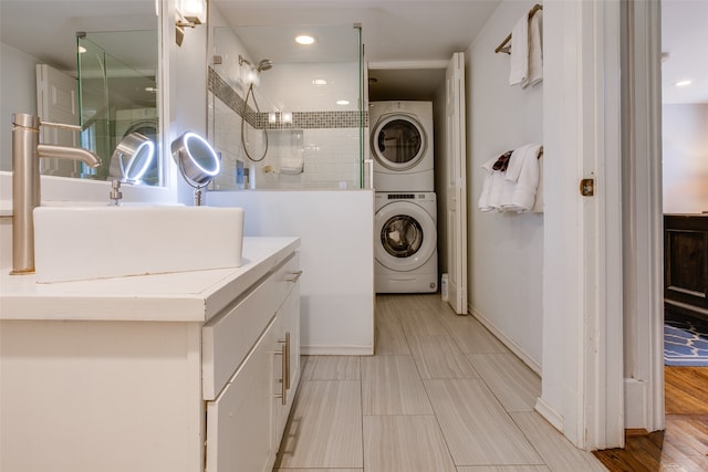 laundry area with sink, stacked washer / dryer, and light hardwood / wood-style flooring