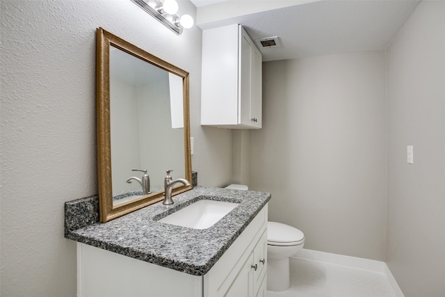 bathroom with vanity, toilet, and a textured ceiling