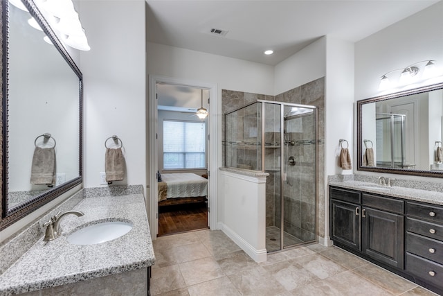 ensuite bathroom with a shower stall, two vanities, and a sink