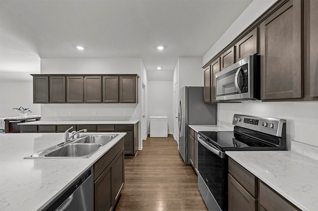 kitchen featuring light stone countertops, sink, stainless steel appliances, dark brown cabinetry, and dark wood-type flooring