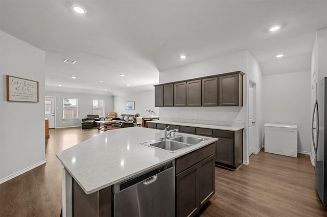 kitchen with a kitchen island with sink, dark brown cabinets, sink, appliances with stainless steel finishes, and dark hardwood / wood-style flooring