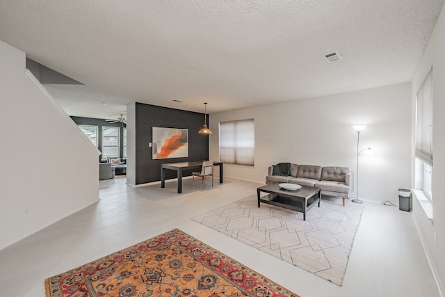 living room featuring a textured ceiling, light hardwood / wood-style floors, and ceiling fan