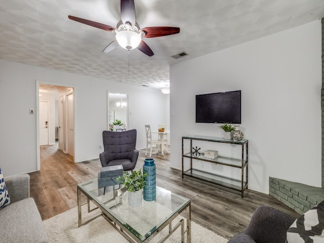 living room with hardwood / wood-style floors, a textured ceiling, and ceiling fan