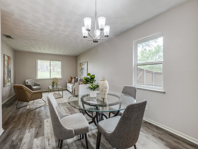 dining area featuring an inviting chandelier, wood-type flooring, and plenty of natural light