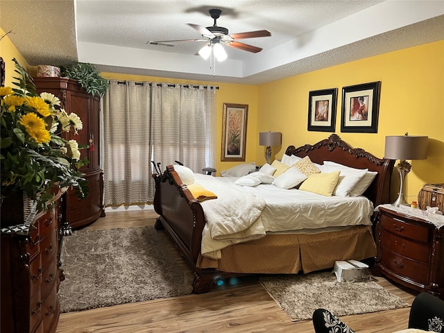 bedroom featuring light hardwood / wood-style flooring, a textured ceiling, and ceiling fan