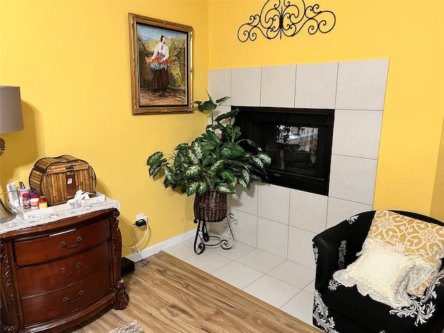 living area featuring a tiled fireplace and light hardwood / wood-style floors