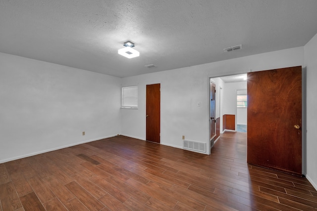 empty room with dark wood-type flooring and a textured ceiling