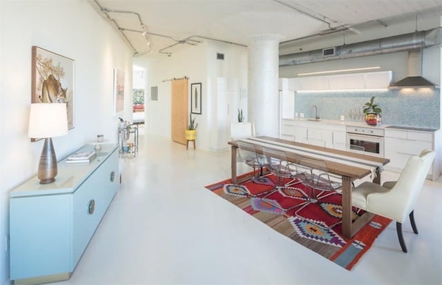 kitchen featuring white cabinetry, decorative backsplash, wall chimney exhaust hood, and oven