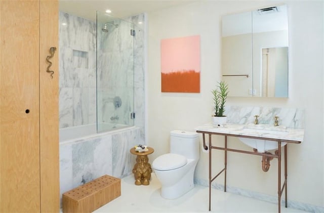 full bathroom featuring tiled shower / bath combo, toilet, and sink