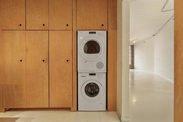 clothes washing area featuring cabinets and stacked washer / drying machine