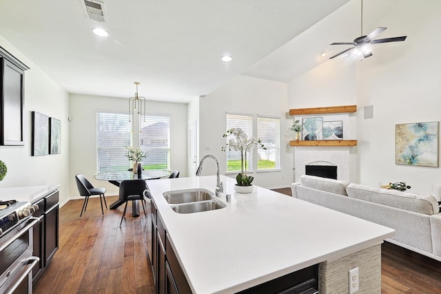 kitchen featuring sink, a fireplace, dark hardwood / wood-style flooring, pendant lighting, and a kitchen island with sink