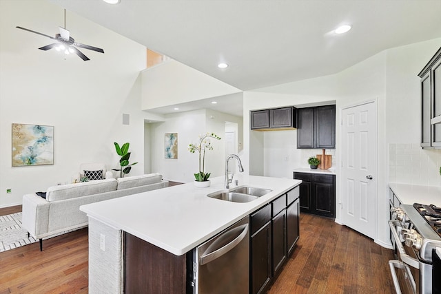 kitchen with appliances with stainless steel finishes, sink, dark brown cabinetry, dark hardwood / wood-style floors, and a kitchen island with sink