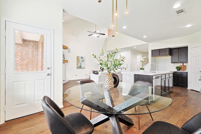 dining space with sink, ceiling fan, high vaulted ceiling, and light hardwood / wood-style flooring