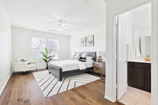 bedroom featuring ceiling fan, ensuite bathroom, and light wood-type flooring