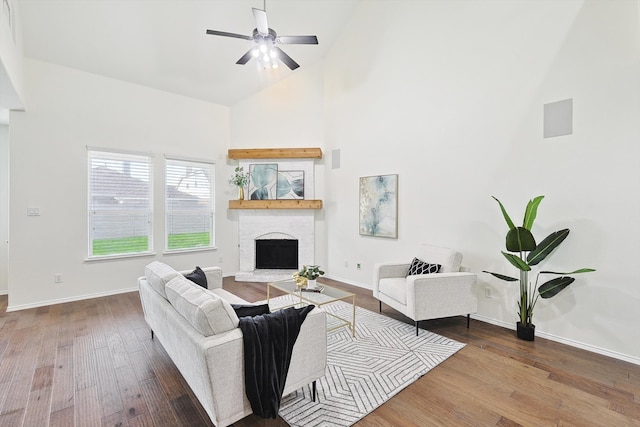 living room with high vaulted ceiling, wood-type flooring, a fireplace, and ceiling fan