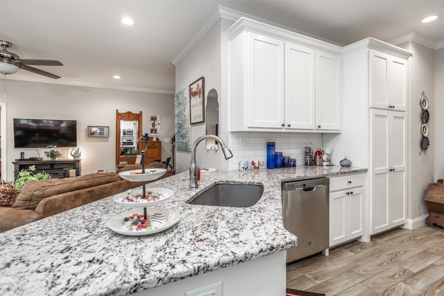 kitchen featuring sink, light stone countertops, stainless steel dishwasher, white cabinetry, and tasteful backsplash