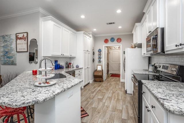 kitchen with appliances with stainless steel finishes, sink, white cabinets, and light stone counters