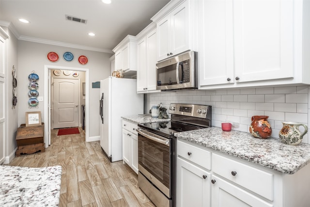 kitchen featuring white cabinets, tasteful backsplash, appliances with stainless steel finishes, ornamental molding, and light hardwood / wood-style floors