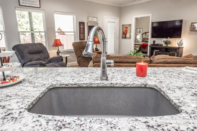 kitchen featuring ornamental molding, light stone countertops, and sink