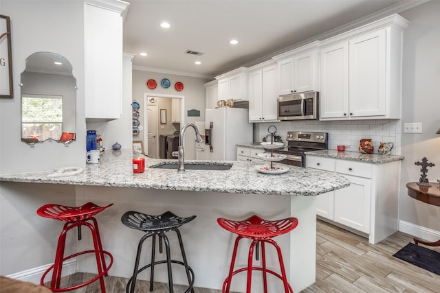 kitchen featuring sink, stainless steel appliances, kitchen peninsula, and white cabinets