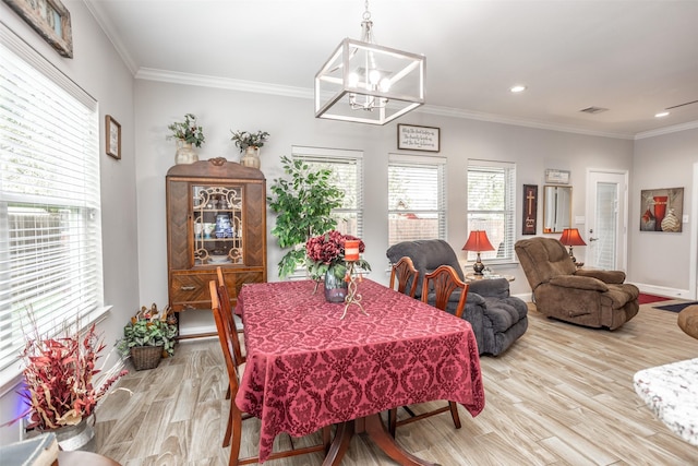 dining room with an inviting chandelier, ornamental molding, and light hardwood / wood-style floors