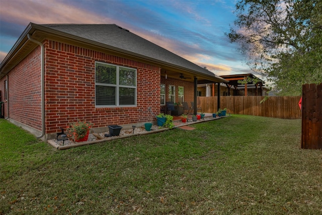 back house at dusk featuring a lawn