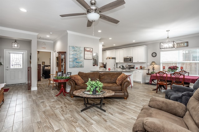 living room with crown molding, ceiling fan with notable chandelier, and a healthy amount of sunlight