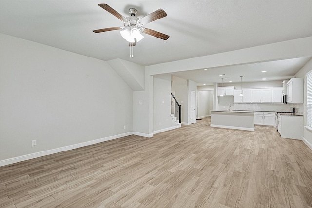 unfurnished living room with light hardwood / wood-style floors, ceiling fan, and sink