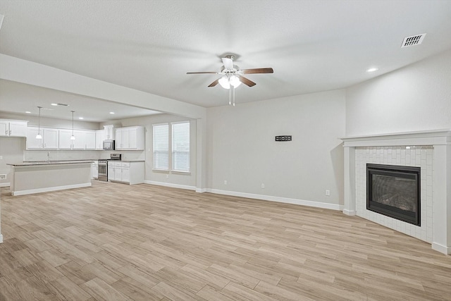 unfurnished living room with ceiling fan, light hardwood / wood-style floors, and a textured ceiling