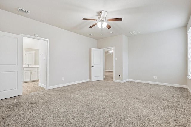 unfurnished bedroom featuring ensuite bath, ceiling fan, and light colored carpet