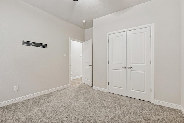 unfurnished bedroom with light colored carpet and a closet