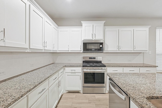 kitchen with white cabinets, light stone counters, and stainless steel appliances