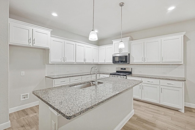 kitchen featuring pendant lighting, white cabinets, sink, light stone countertops, and stainless steel appliances