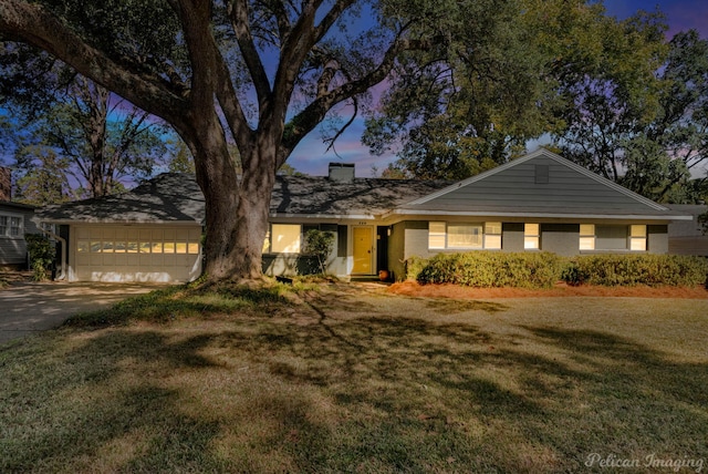 ranch-style house with a garage and a yard