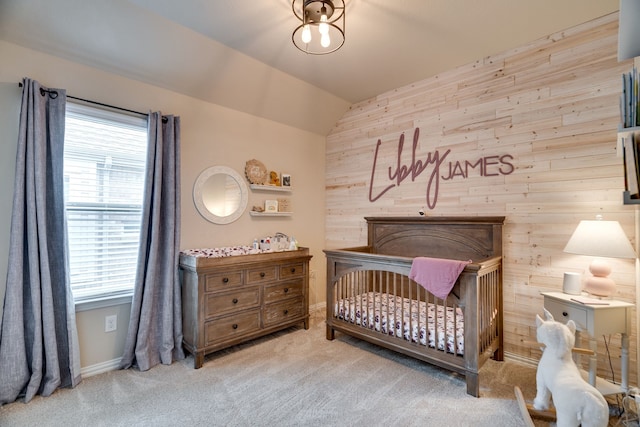 bedroom featuring vaulted ceiling, light carpet, wooden walls, and a nursery area