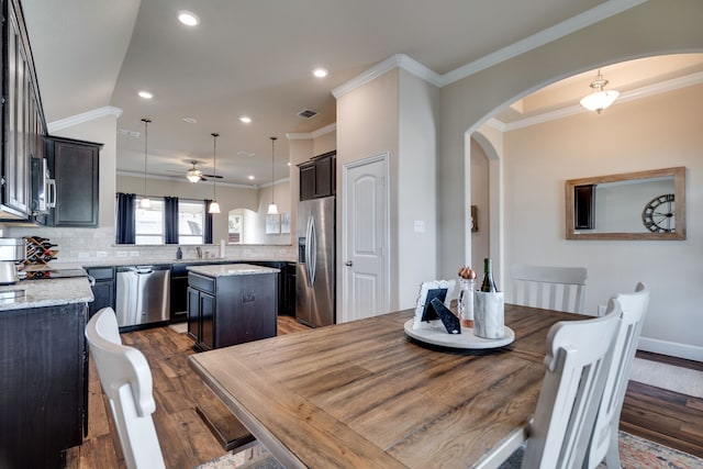 dining space with ceiling fan, dark hardwood / wood-style flooring, ornamental molding, and sink