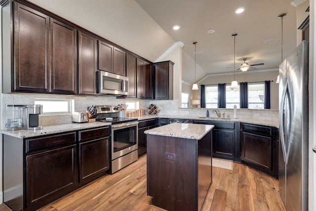 kitchen featuring a center island, stainless steel appliances, kitchen peninsula, pendant lighting, and lofted ceiling