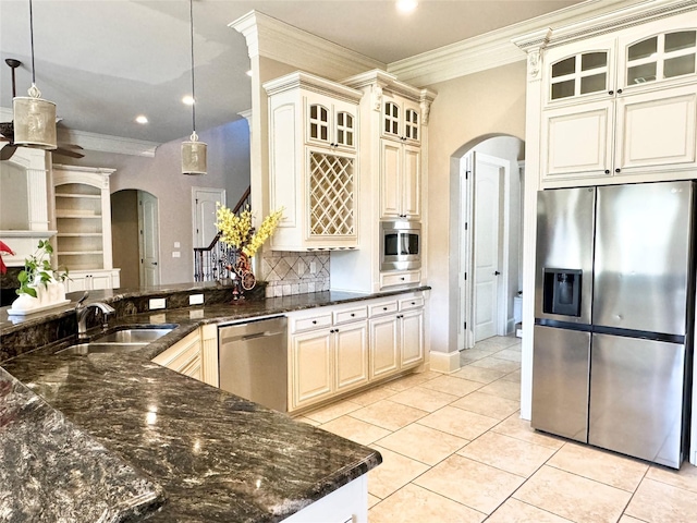 kitchen with arched walkways, stainless steel appliances, and cream cabinetry