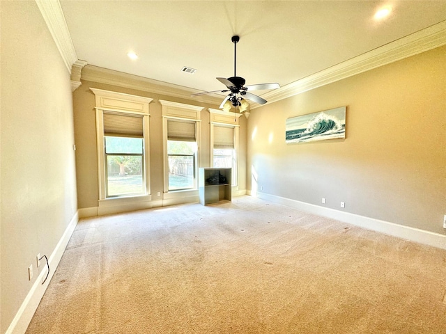 unfurnished living room with ceiling fan, light colored carpet, visible vents, baseboards, and ornamental molding