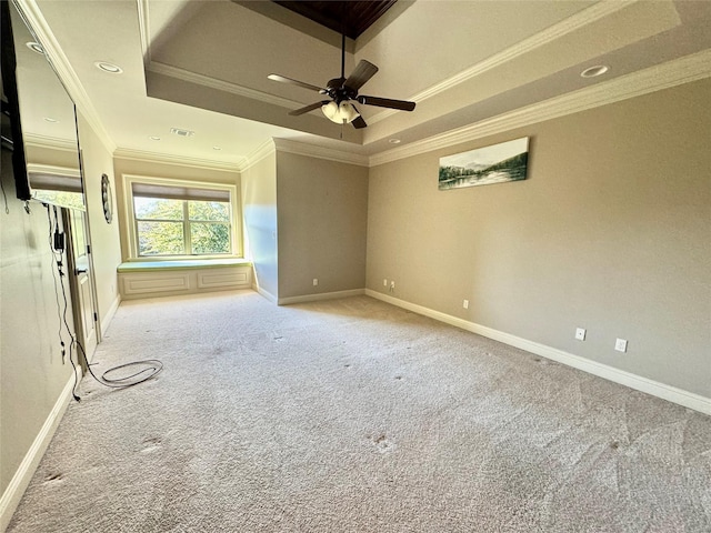 spare room with a tray ceiling, carpet flooring, visible vents, and baseboards