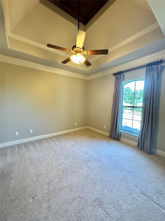 carpeted spare room featuring ceiling fan, baseboards, a raised ceiling, and crown molding