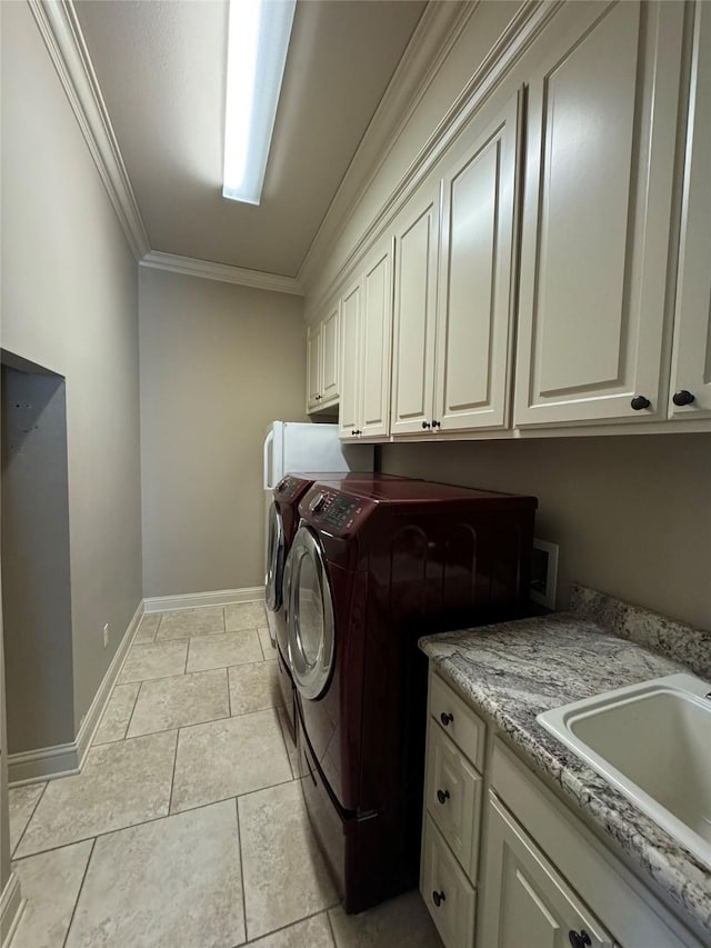 washroom with a sink, baseboards, cabinet space, washer and clothes dryer, and crown molding