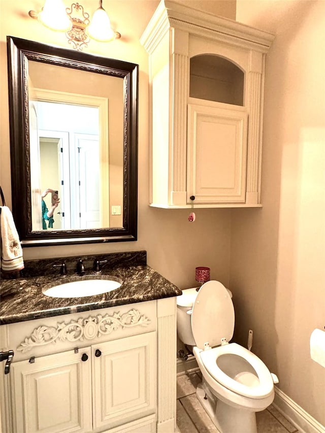 bathroom with toilet, baseboards, and vanity