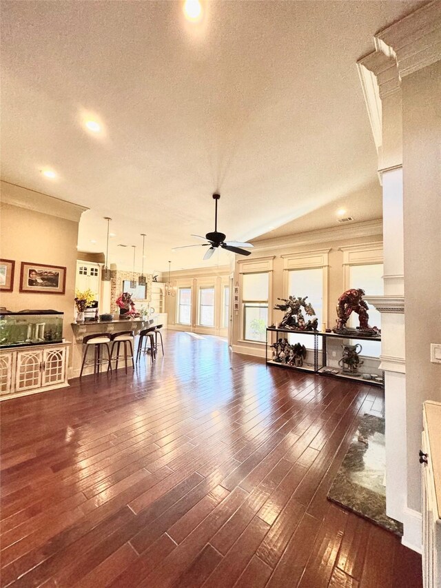 living area with dark wood-style floors, crown molding, a textured ceiling, and a ceiling fan