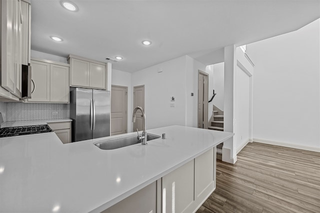 kitchen with kitchen peninsula, appliances with stainless steel finishes, sink, and light wood-type flooring